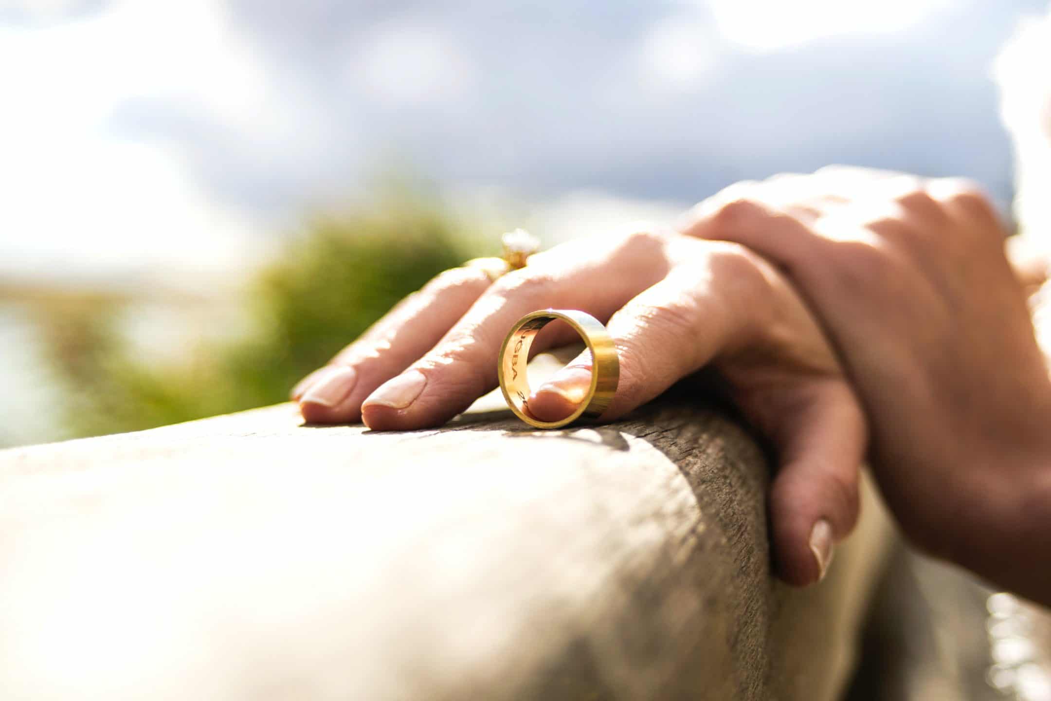 a person's hand rests on a low wall with their wedding ring slipped off
