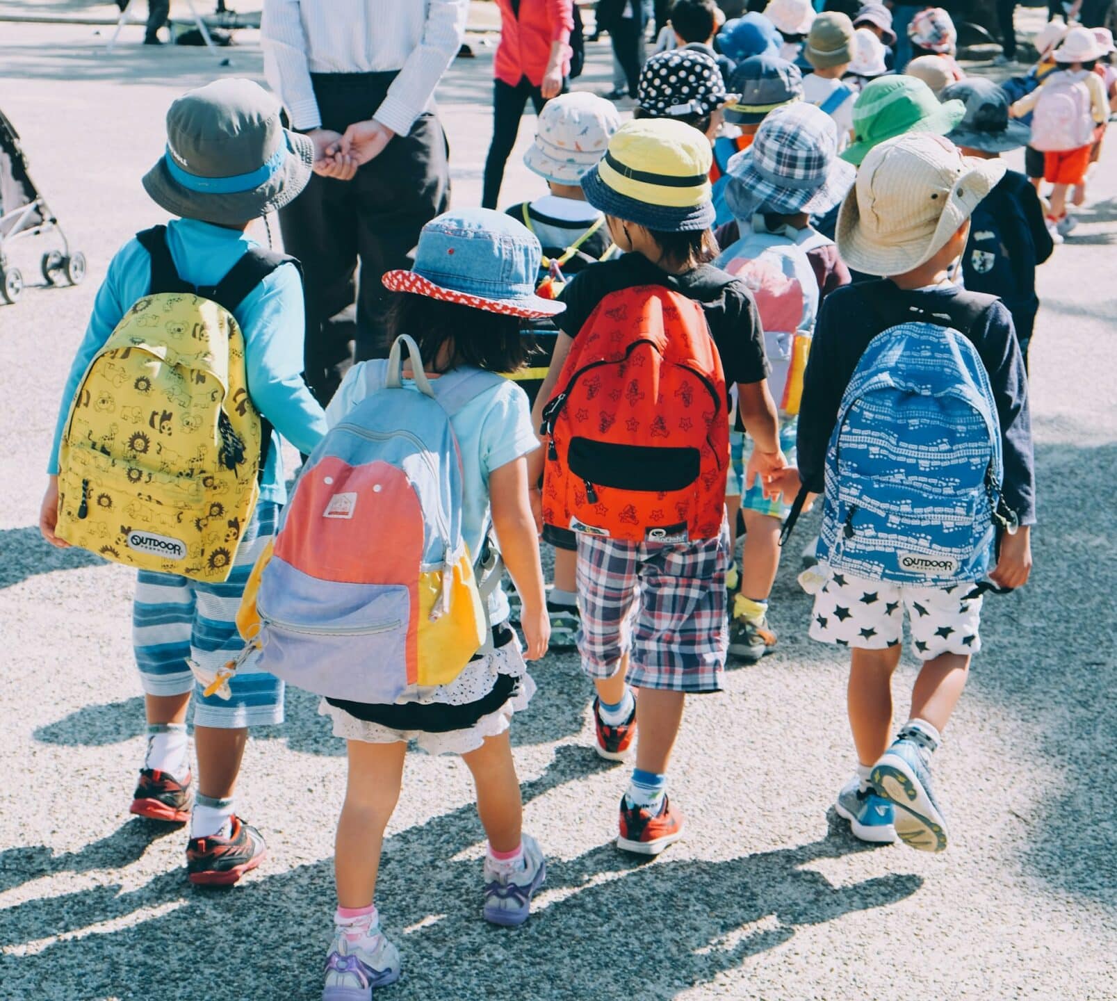 A group of school children holding hands and wearing backpacks while on a field trip, representing child support section 7 expenses.