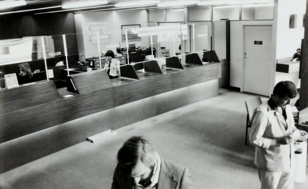 A black and white image of the teller counter at a bank, representing fraud and banks.