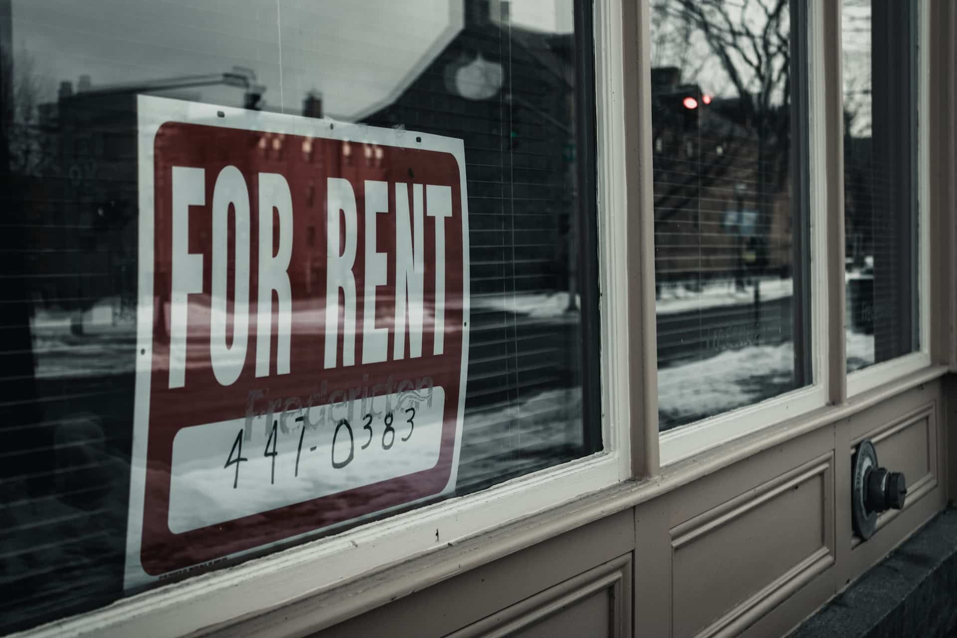 A for rent sign with a phone number is mounted in one of three windows of a building, representing BC short term rental laws.