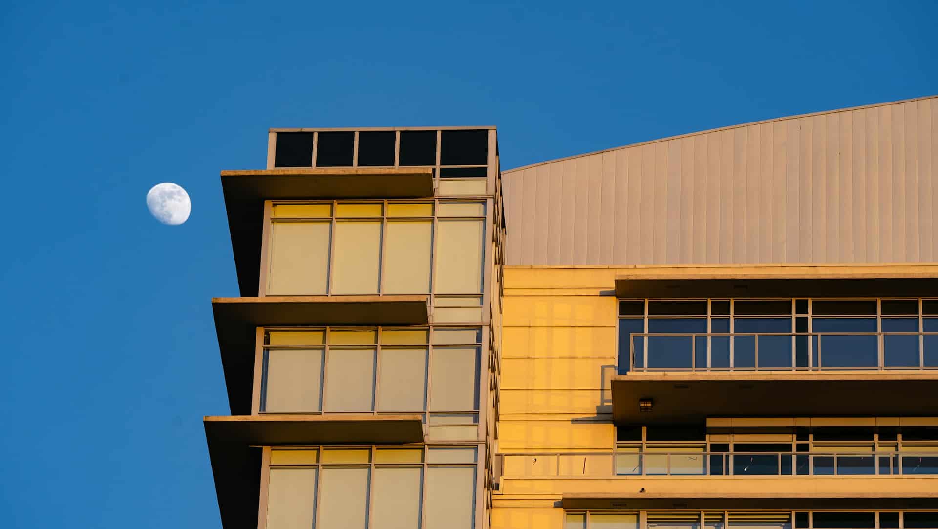A midcentury modern-style condominium building in Vancouver against a half-moon in the sky, representing beneficial ownership, co-ownership, and Partition of Property Act disputes in BC