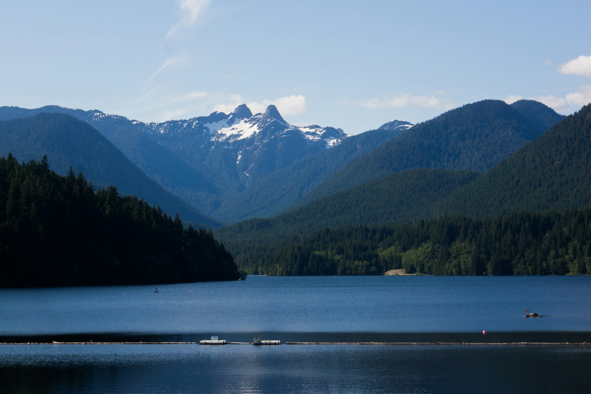 A lake with mountains in the background and blueskies simulating what no-build covenant in Indian Arm, British Columbia.