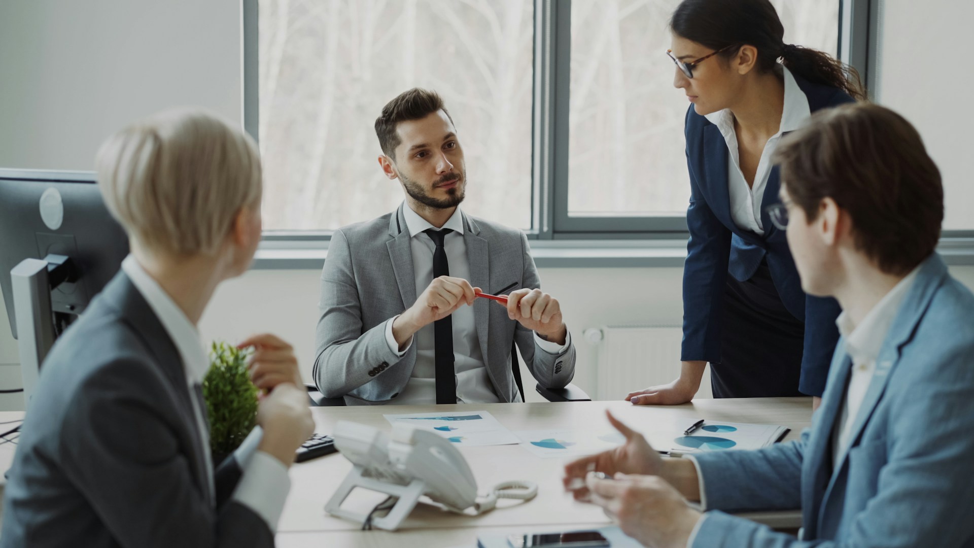 A businessman meets with male and female colleagues around a meeting table with documents scattered on the surface in modern office, representing oppression remedy in BC.