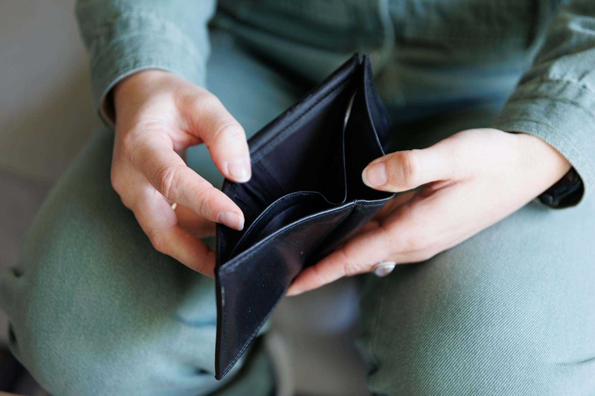 Someone visible from the waist dow sits with an empty wallet in their lap, representing hidden income in child and spousal support.