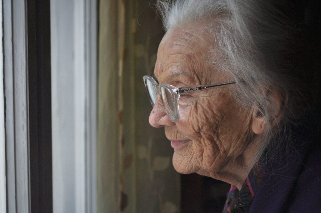 A close up of an elderly woman's profile. She has thin, silver hair and wears clear plastic-framed glasses, representing capacity and will disputes in BC.