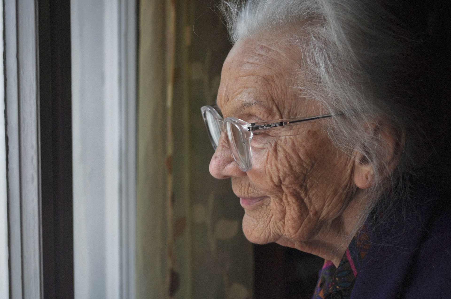 A close up of an elderly woman's profile. She has thin, silver hair and wears clear plastic-framed glasses, representing capacity and will disputes in BC.