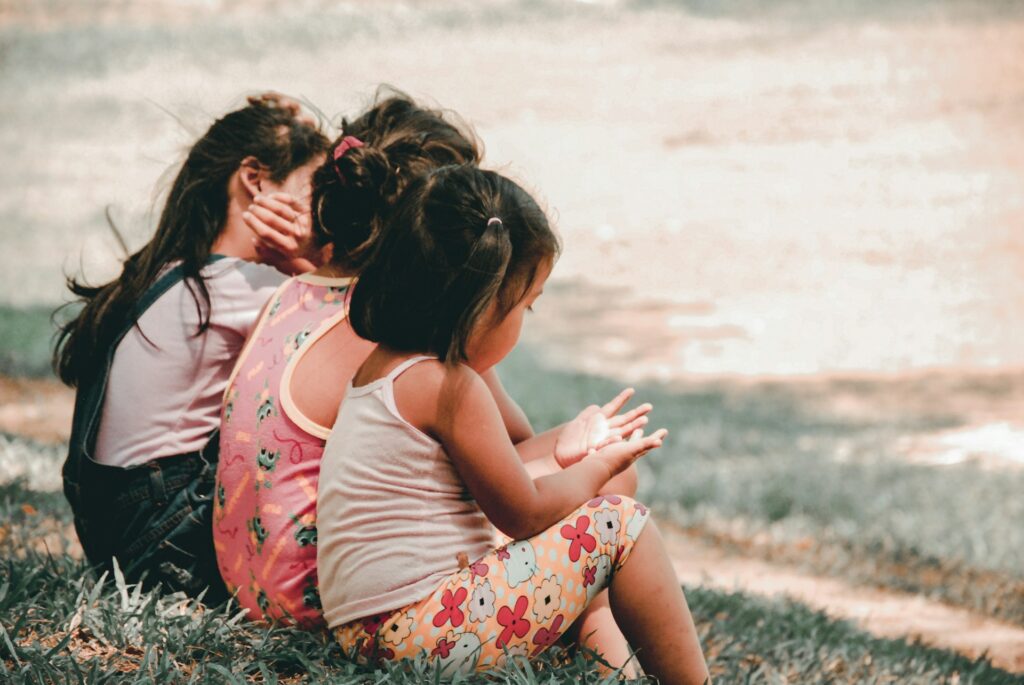Three children sitting on grass representing how BC courts address child support, parenting reloaction and child support.