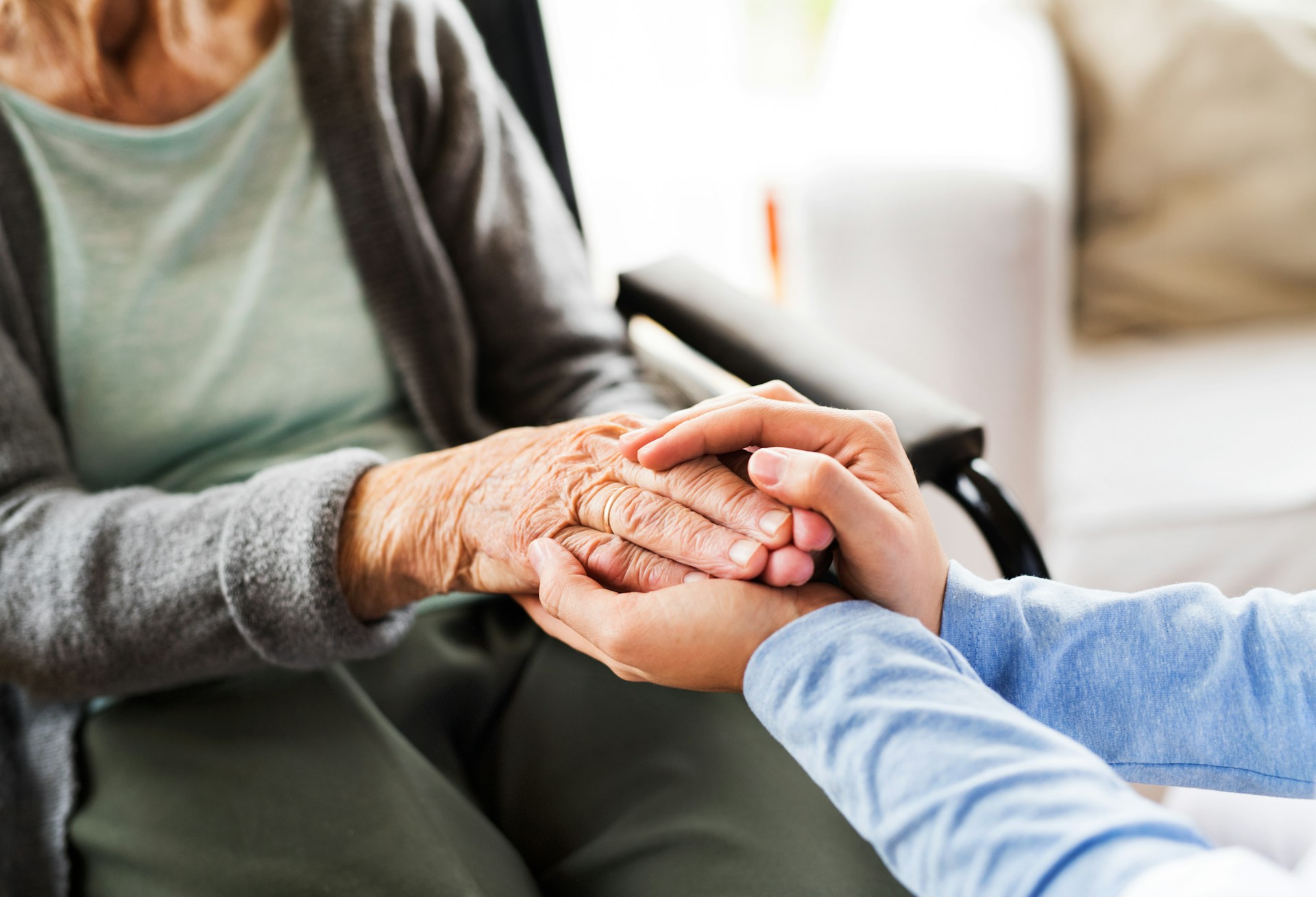 A person holding a senior persons hand while they sit in a wheelchair, this photo could be representing Contested Committeeships in BC.