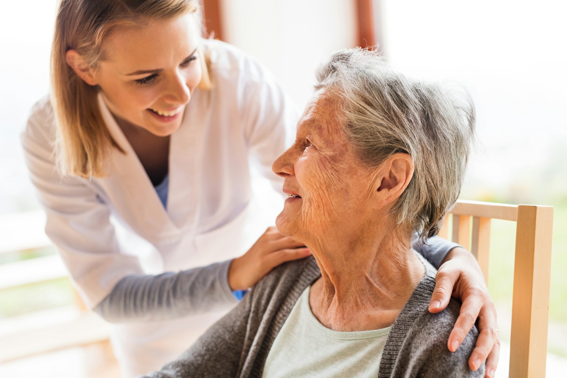 A young female caregiver smiling at an elderly woman, representing committeeship applications in Vancouver, British Columbia.